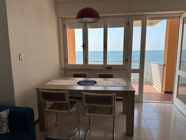 Zona pranzo dell'appartamento con vista sul mare attraverso le ampie vetrate, Grado