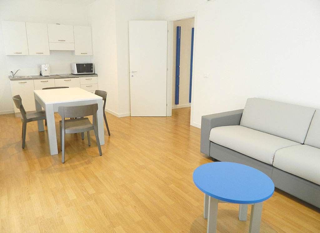Zona giorno con angolo cottura e divano dell'appartamento Deluxe 60 mq, Palamostre Residence, Udine